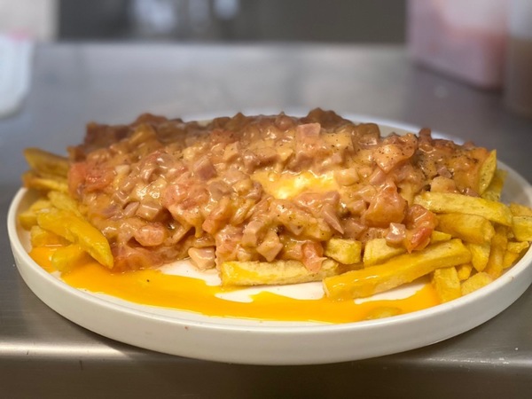 Huevos rotos con lacón, tomate concassé, queso cheddar, jalea de cebolla y patatas fritas