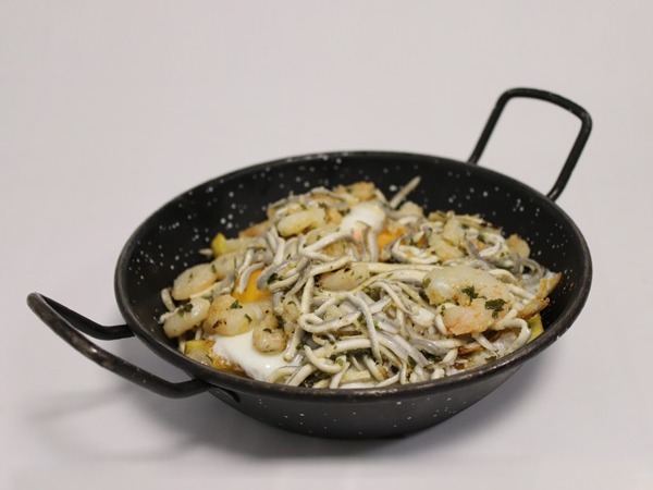 Cazuela de huevos rotos con gulas y gambas.