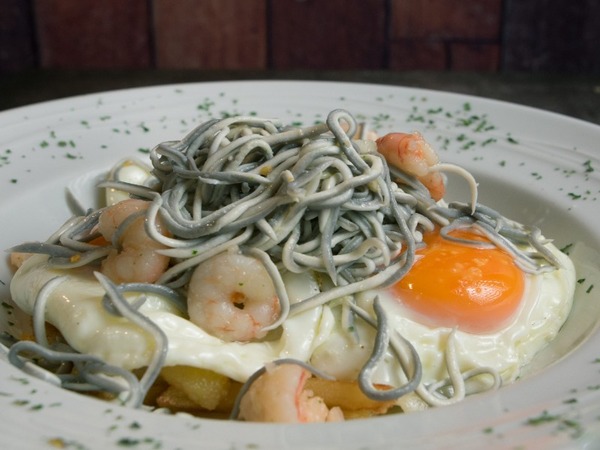 Huevos rotos con gulas, gambas y tallarines negros de sepia 